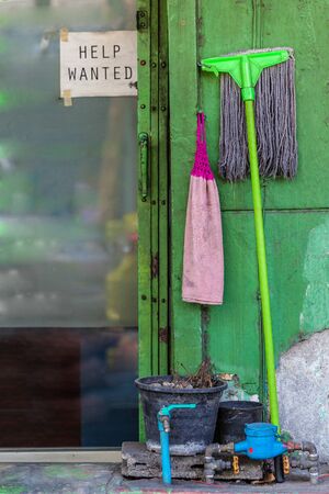 a help wanted sigh on the showcase window of a small shop near a dirty mopの写真素材