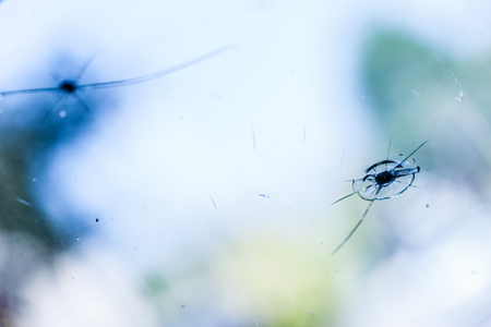 two bullet impact cracks on the windshield of a carの写真素材