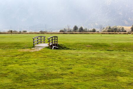 an old wooden bridge on an idyllic meadow or a beautiful golf courseの写真素材