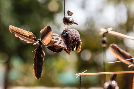 a homemade wooden bird shaped wind toy with feathers hanged with a string
