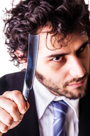a young and handsome businessman holding a cut-throat razor isolated over a white backgroundの写真素材
