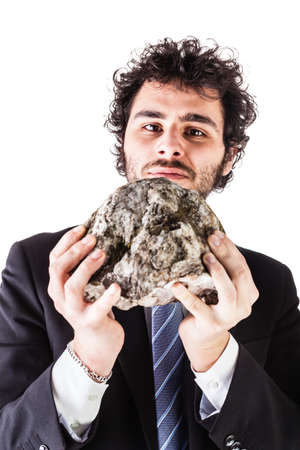 a businessman wearing a suit and a tie holding a heavy rock isolated over a white backgroundの写真素材