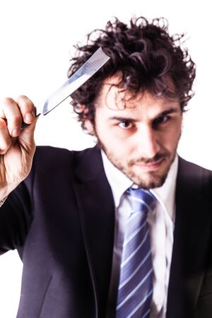 a young and handsome businessman holding a cut-throat razor isolated over a white backgroundの写真素材