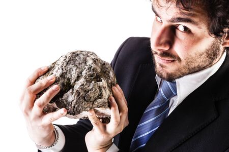 a businessman wearing a suit and a tie holding a heavy rock isolated over a white backgroundの写真素材