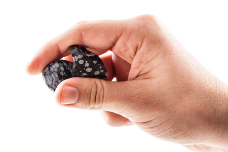 a male hand holding a fragment of obsidian mineral isolated on a white background