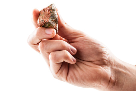 a male hand holding a fragment of unakite mineral isolated on a white background