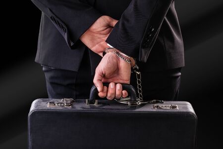 Businessman wearing a suit with a secure suitcase attached with handcuffs
