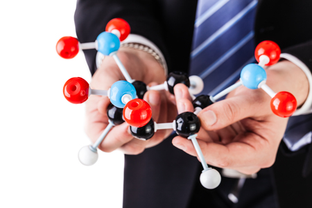 a businessman wearing a suit and a tie holding a trinitrotoluene tnt molecular model isolated over whiteの写真素材