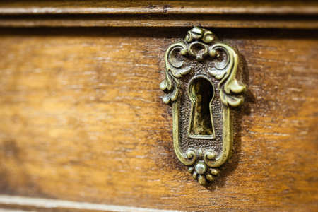 an antique and weathered keyhole on a desk drawerの写真素材