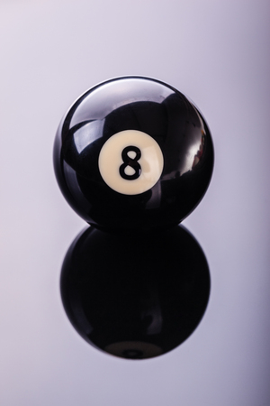 a pool black eight ball shot over a dark reflective surface