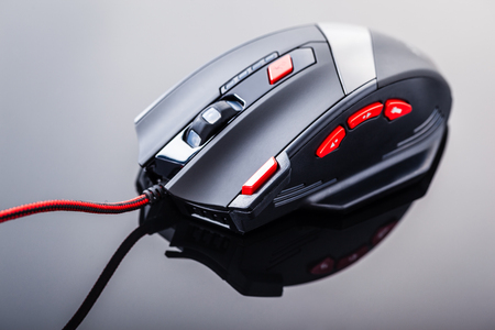 a sleek modern gaming mouse with red buttons over a dark shiny surfaceの写真素材