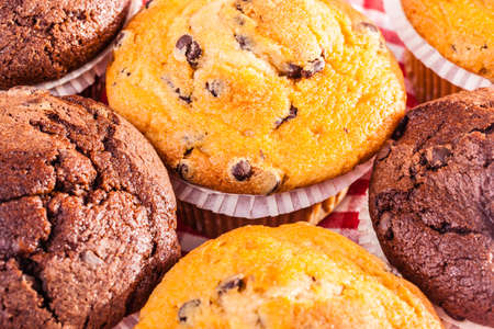 some delicious homemade muffins with chocolate drops on a red and white checkered tablecloth