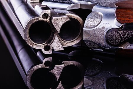 detail of the breech of a classic vertical over-under double barreled shotgun over a dark surfaceの写真素材
