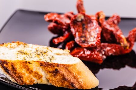 dried tomatoes on a modern plate shot on a black reflective surfaceの写真素材