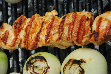 Sizzling chicken and sausages kebabs and vegetables on hot barbecue grillの写真素材