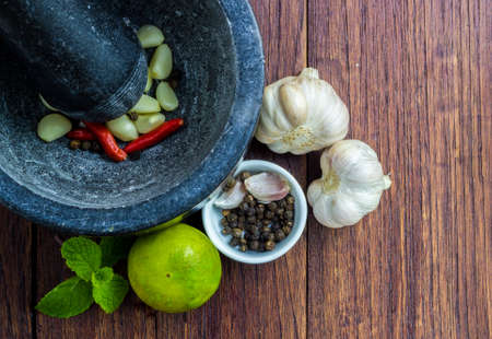 Mix of Thai herb ingredient with Pestle and mortar on a wooden table