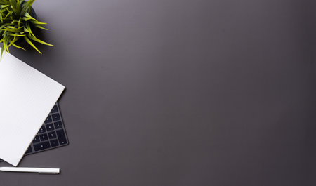 Workplace in office with black desk. Top view from above of keyboard with notebook and phone. Space for modern creative work of designer. Flat lay with blank copy space. Business and finance concept.の写真素材