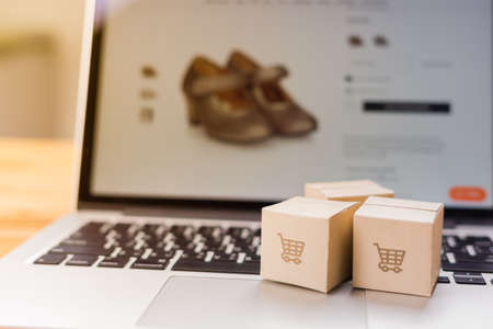 Online shopping - Paper cartons or parcel with a shopping cart logo on a laptop keyboard which web...