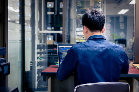 Technicians using laptop while analyzing server in server room,System security specialist working at system controcenterの写真素材