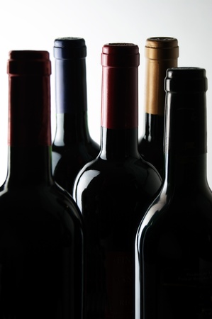 Five bottles of wine in a dark room lit from above.の写真素材