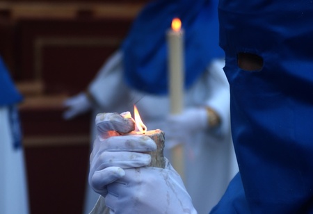 Nazarene carrying a candle in a procession