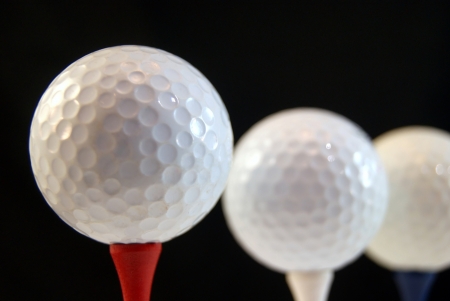 Golf ball on tee, isolated on blackの写真素材