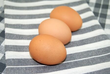 Fresh eggs on striped tablecloth, closeup