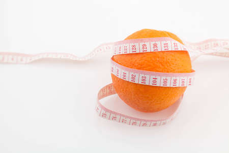 Orange fruit surrounded by a tape measure on white backgroundの写真素材