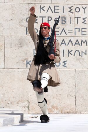 ATHENS, GREECE - JULY 23: Evzones (presidential guards) watches over the monument of the Unknown Soldier in front of the Greek Parliament Building at Syntagma Square on July 23, 2010 in Athens, Greece. Evzoni, is the name of historical elite mountain unitのeditorial素材
