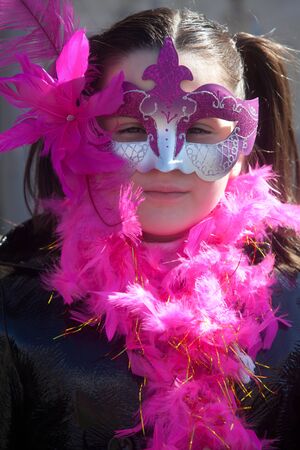ALEXANDROUPOLIS, GREECE - FEB 25: Unidentified participant of carnival parade in Alexandroupolis on February 25, 2012 in Alexandroupolis, Greece. Little girl with pink maskのeditorial素材