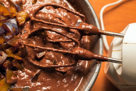 Stirring with electric whisk the ingredients for a chocolate cake with fruitsの写真素材