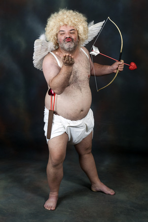 Fat bearded mature hairy cupid with bow and heart arrow. Sending a kissの写真素材