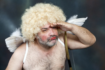 Fat bearded mature hairy cupid with bow and heart arrow.の写真素材