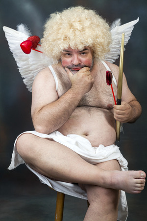 Fat bearded mature hairy cupid with bow and heart arrow.の写真素材