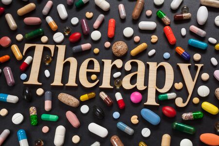 Word THERAPY with wooden letters surrounded by colorful pillsの写真素材