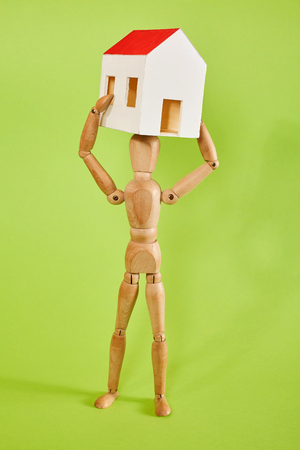 Dummy carrying small house on green backgroundの写真素材