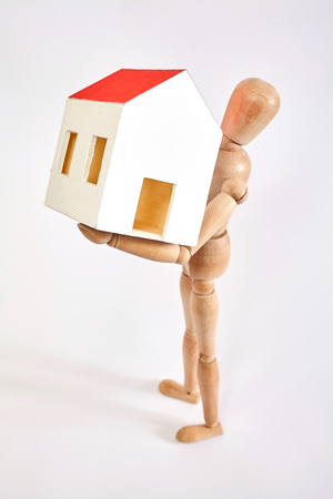 Dummy carrying small house on white backgroundの写真素材