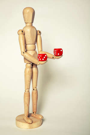 Wooden puppet holds dice on white backgroundの写真素材