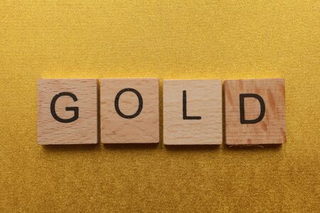 Wooden letters spelling GOLD on yellow backgroundの写真素材