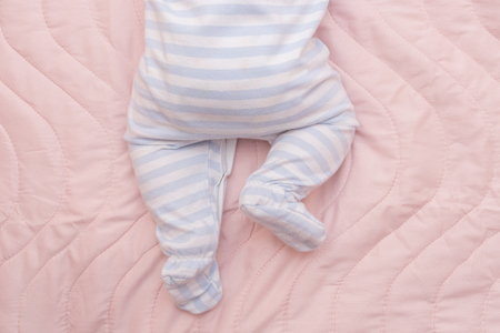 Newborn baby boy lying on bed, close up of his legsの写真素材