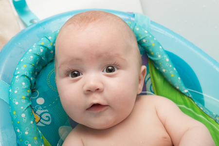 Portrait of a cute baby boy sitting in bath. Adorable seven month old happy child laughing.の写真素材