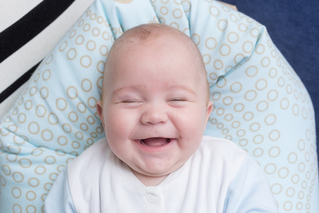 Portrait of a cute baby boy sitting and smiling. Adorable seven month old child happy laughing.の写真素材