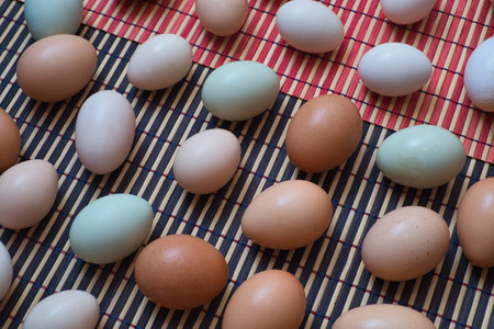Eggs in various colors on a mat on the kitchen tableの写真素材