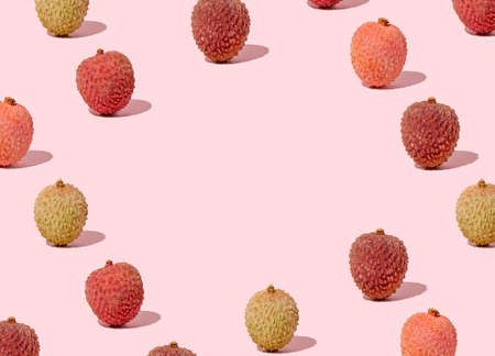 Creative pattern with copy space made with fresh colorful lychees against on pink background. Minimal spring and summer fruit layout.の写真素材