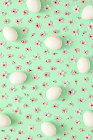 2021 Easter creative pattern made with spring flower and white Easter eggs on pastel green...