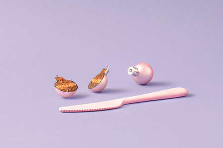Pink Christmas bauble cut in half with a knife. Christmas cake creative idea. Minimal New Year food...