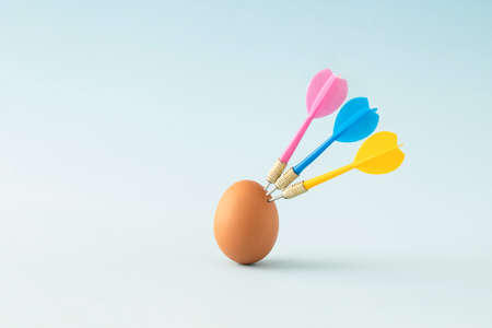 Natural Easter egg with colorful darts. Creative minimal darts game concept.