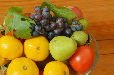 fruit in a glass bowl on a wooden tableの写真素材