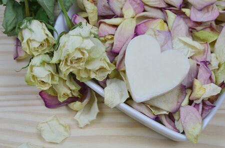 dried white roses and petal with candle heart shape (lens blur)の写真素材