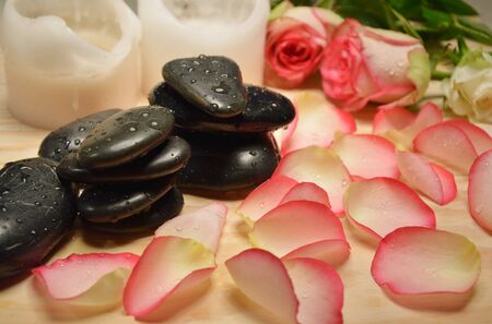 stone massage with pink rose petals and candleの写真素材